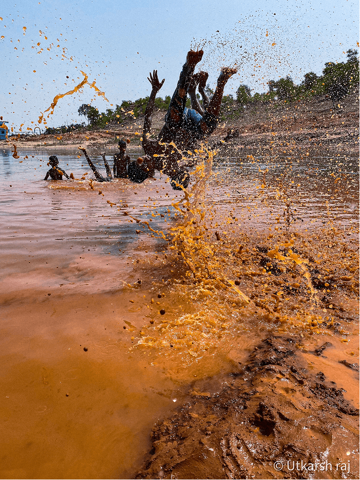 Children diving and splashing in an orange-brown river