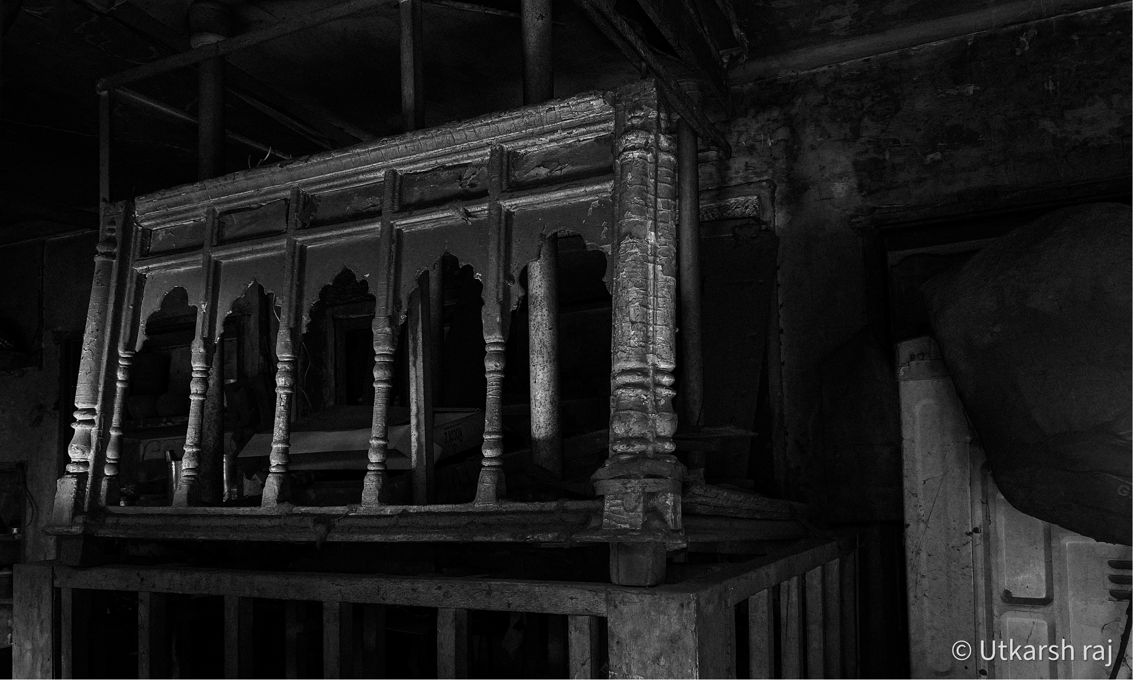 Ornate carved wooden railing inside a dark room