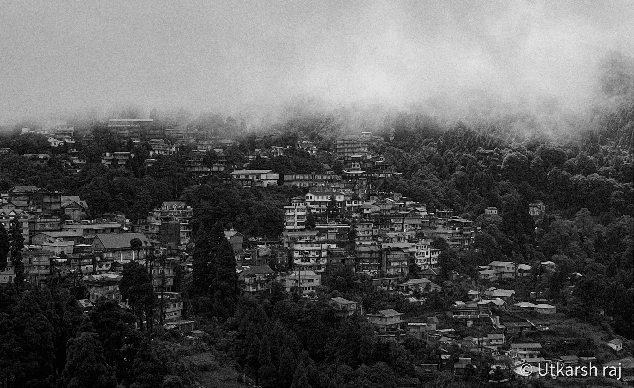 Black and white hill town wrapped in low cloud and fog