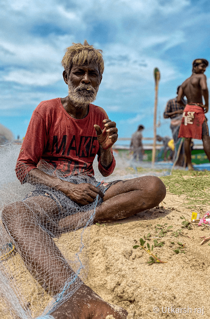 Fisherman mending net on the beach