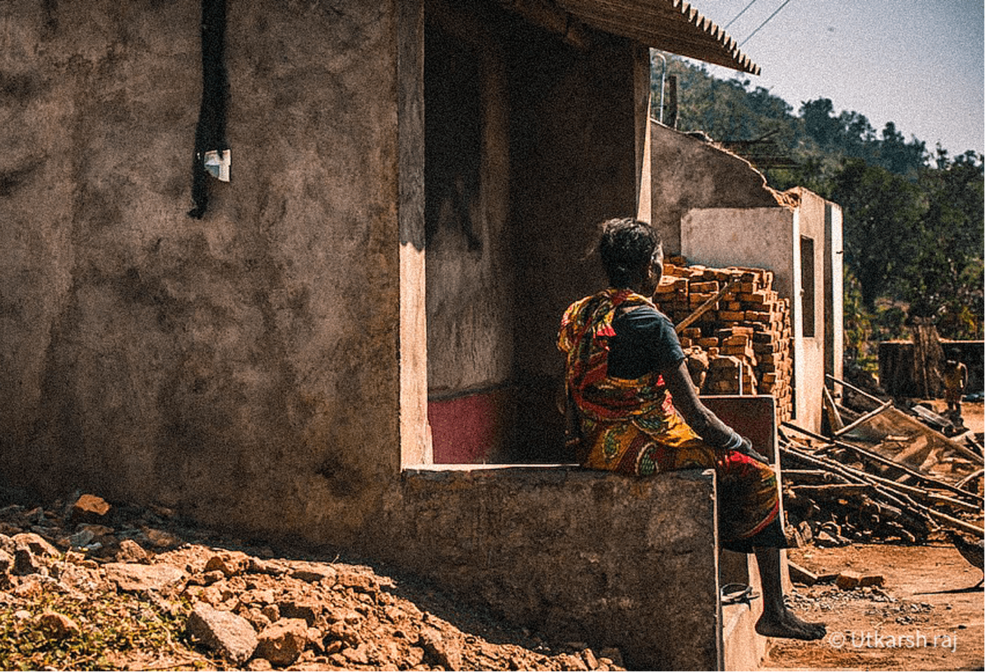 Woman sitting outside a half-built house at a construction site
